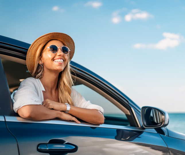 Mujer sonriendo asomándose por la ventanilla de su coche